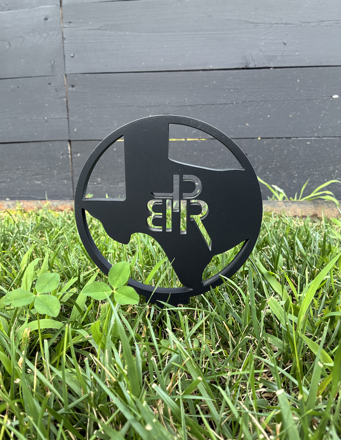 Black circular PR golf sign installed in a grassy landscape