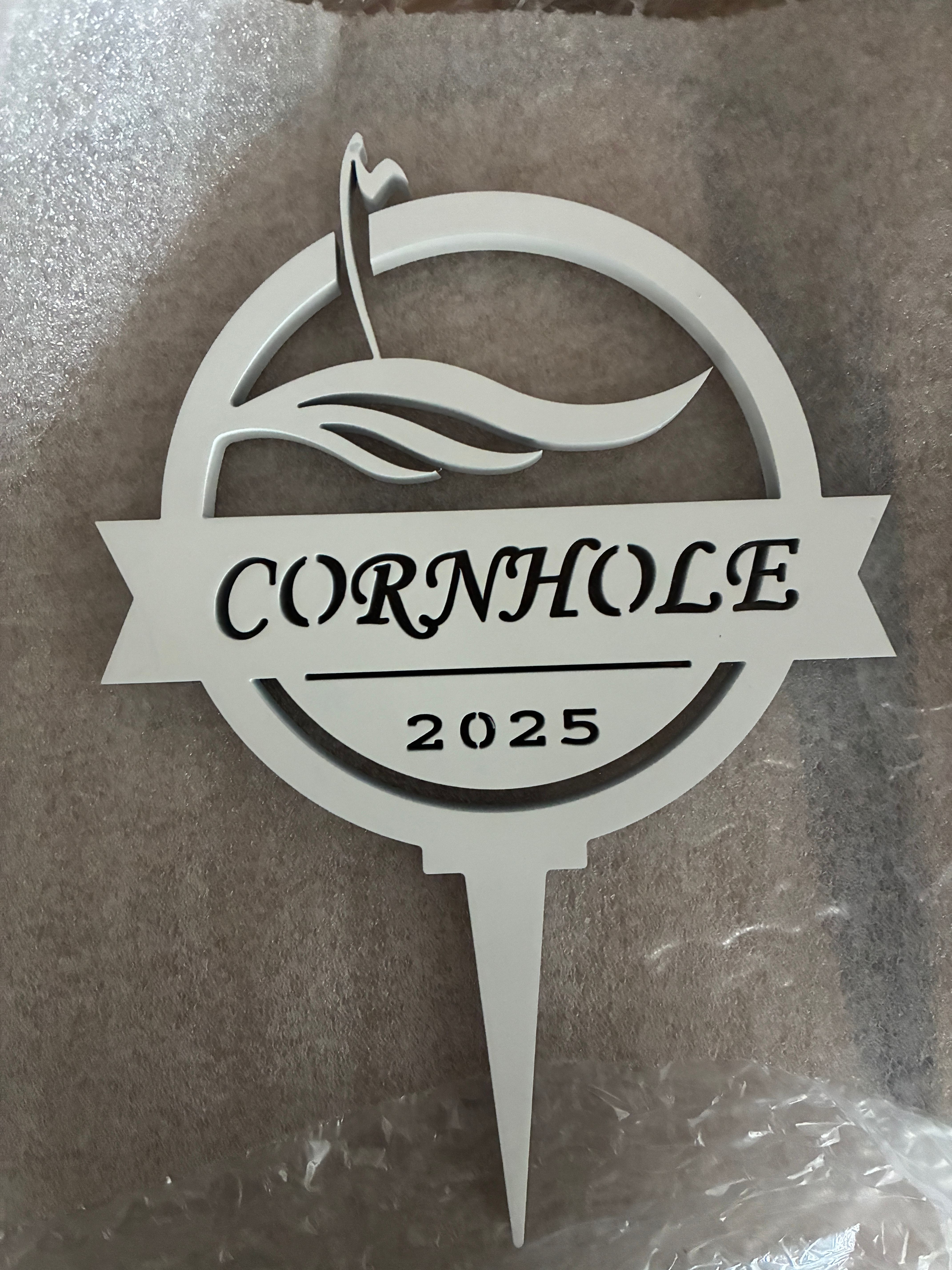 White ornamental golf sign with layered cut-out lettering photographed on a textured surface